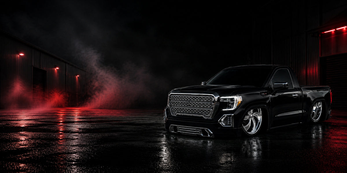 Black lowered single-cab truck on polished Intro billet wheels outside a red-lit warehouse